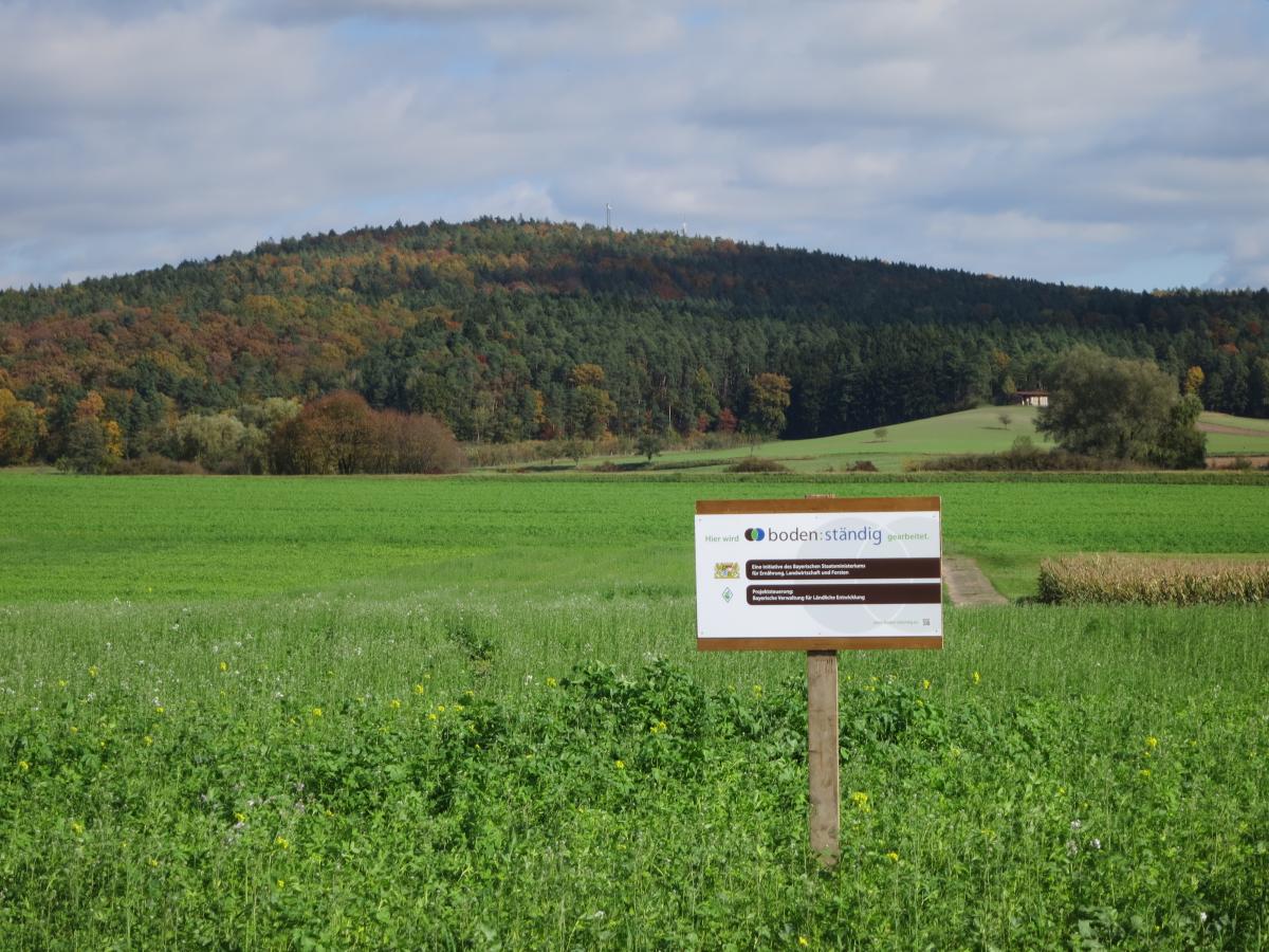 Landschaft mit einem Schild mit der Aufschrift boden:ständig im Vordergrund