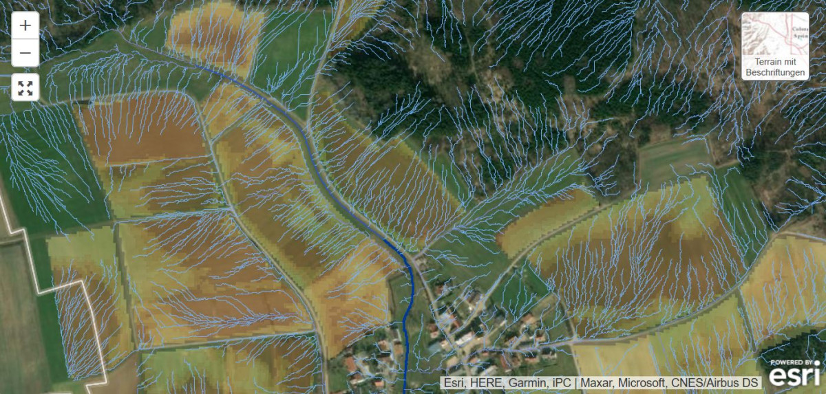 Ausschnitt einer Luftbildkarte mit GIS-berechneten Abflussbahnen: blaue Linien zeigen, wo das Wasser von den Flächen fließt und sich in den Tiefenlinien bündelt. Für Ackerflächen wird außerdem die Erosionsgefährdung nach ABAG dargestellt.