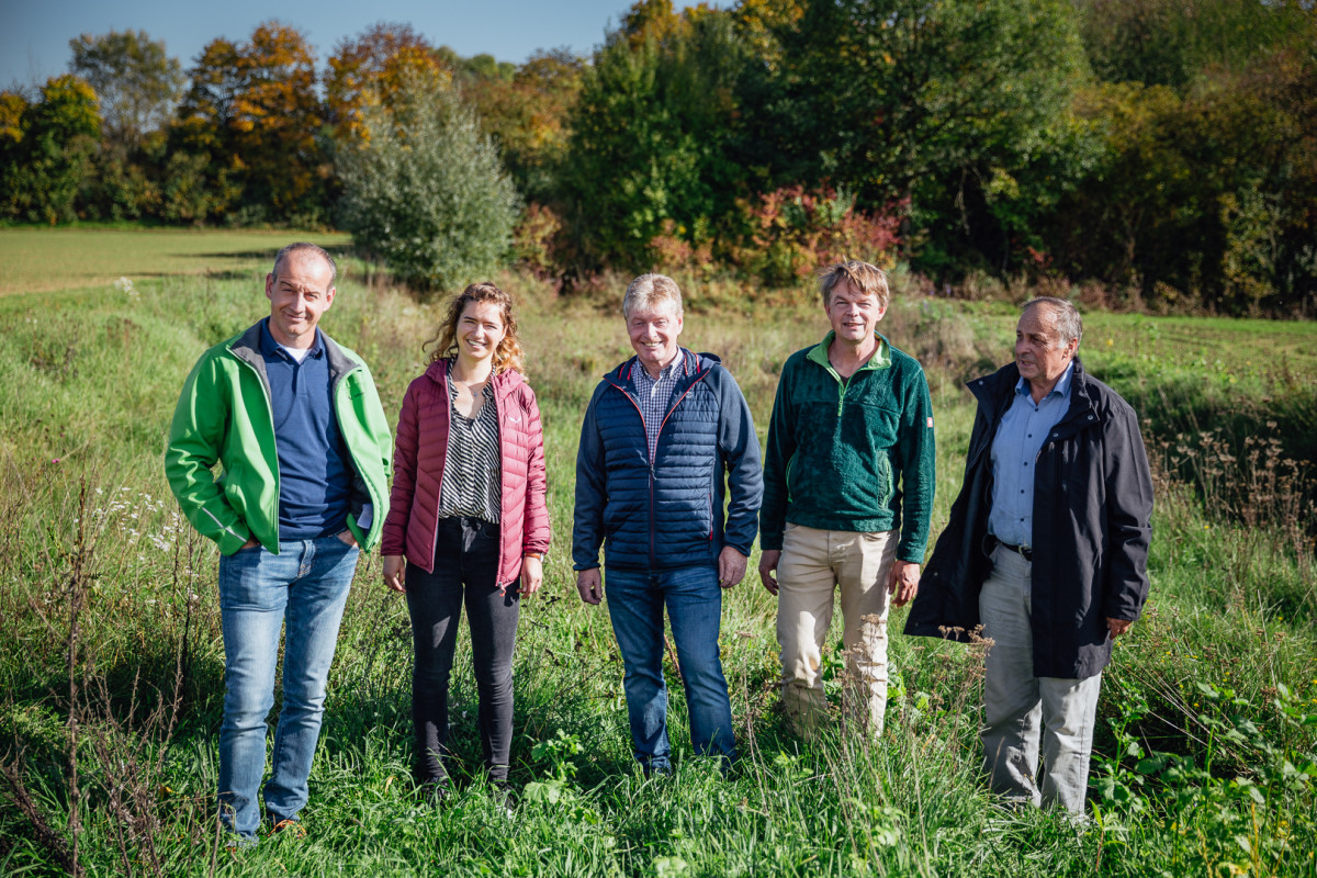 Fünf Personen stehen auf einem grasbewachsenen Dammfuss.