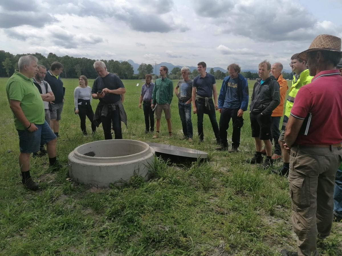 Landwirte und Multiplikatoren informieren sich über Feuchtgrünland und Paludikulturen auf der Versuchsstation Karolinenfeld der Bayerischen Staatsgüter. Johann Pflügler (ganz links) erklärt als Projektleiter den Schachtring: Dort laufen die Dränrohre zusa