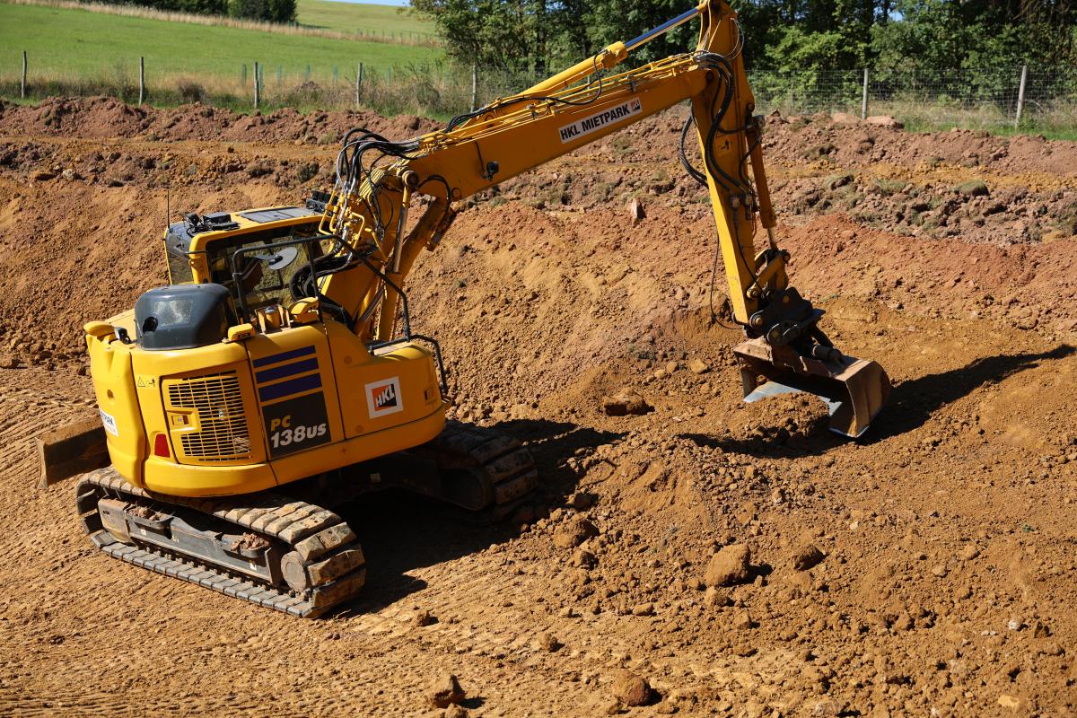 Ein gelber Bagger planiert Erde