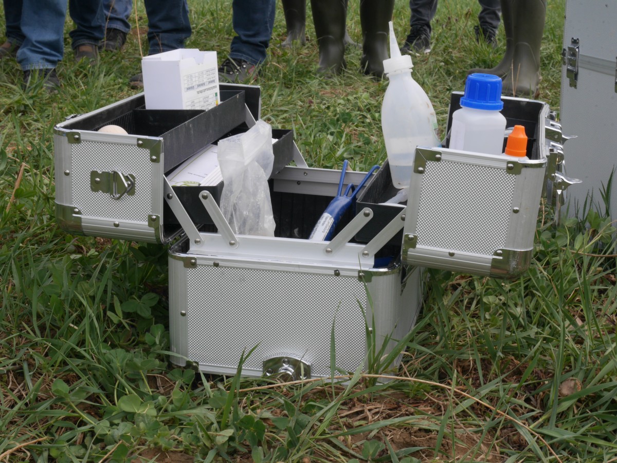 Werkzeugkoffer auf Akcerfläche. Darin diverse Probenflaschen, Handhacke u.a. Zubehör. Symbolbild