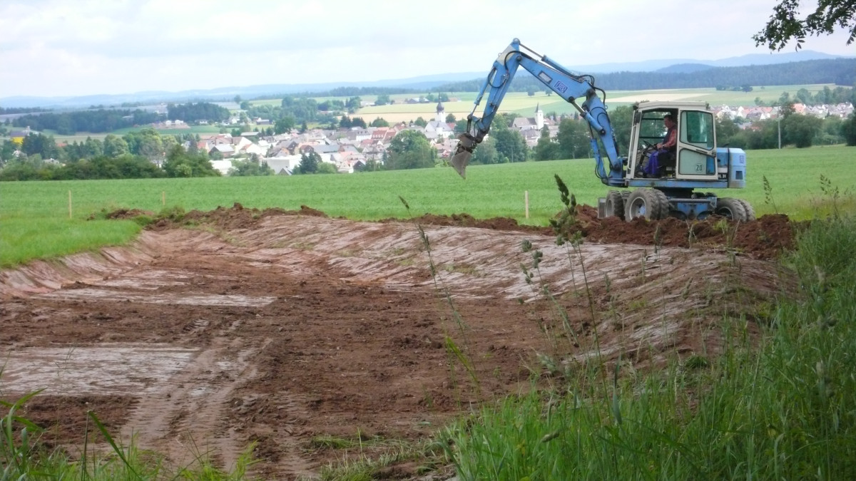 Bagger vor ausgehobenem Rückhaltebecken