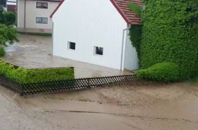 Wasserabfluss aus dem Einzugsgebiet Schulstraße durch den Straßenraum (am linken Bildrand) und durch eine Hofstelle (Bildmitte)