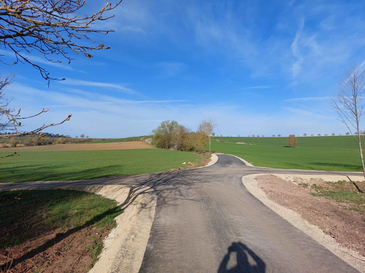 Es ist ein neugebauter, asphaltierter Weg in der Flur zu sehen