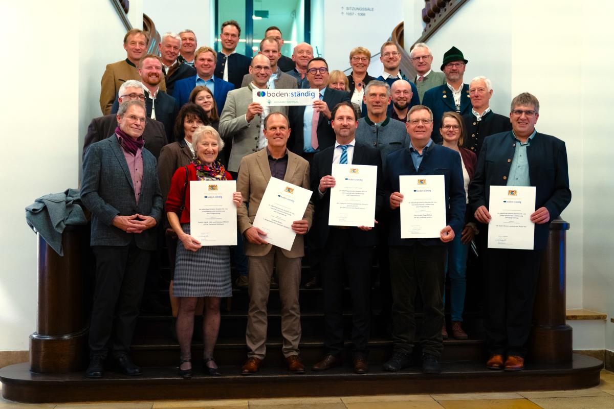Gruppenbild auf der Treppe im Ministerium - mit den Urkunden und einem boden:ständig-Schild