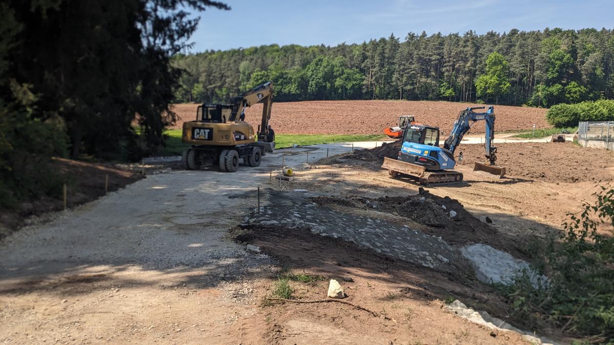 Mehrere mittelgroße Kettenbagger neben einem Weg - offensichtlich wird gerade eine Grube ausgehoben