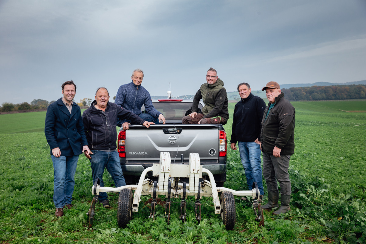 Eine gruppe Männer positioniert sich um ein kleines, weißes Gerät,das an einem Pickup angebaut ist.